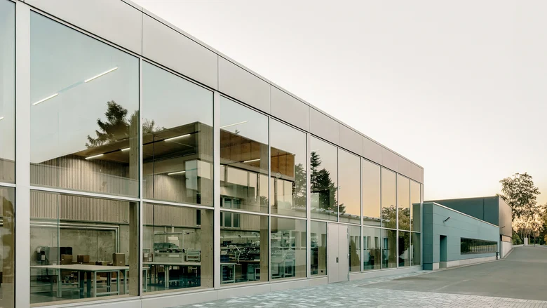 Gebäude mit Glasfront in der sich ein weiteres Gebäude spiegelt