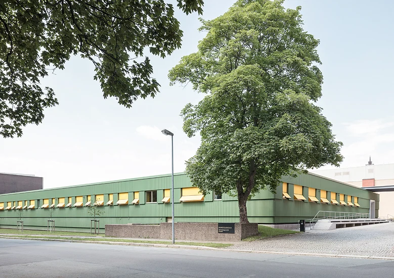 Bild eins grünen Gebäudes mit einem Baum im Vordergrund