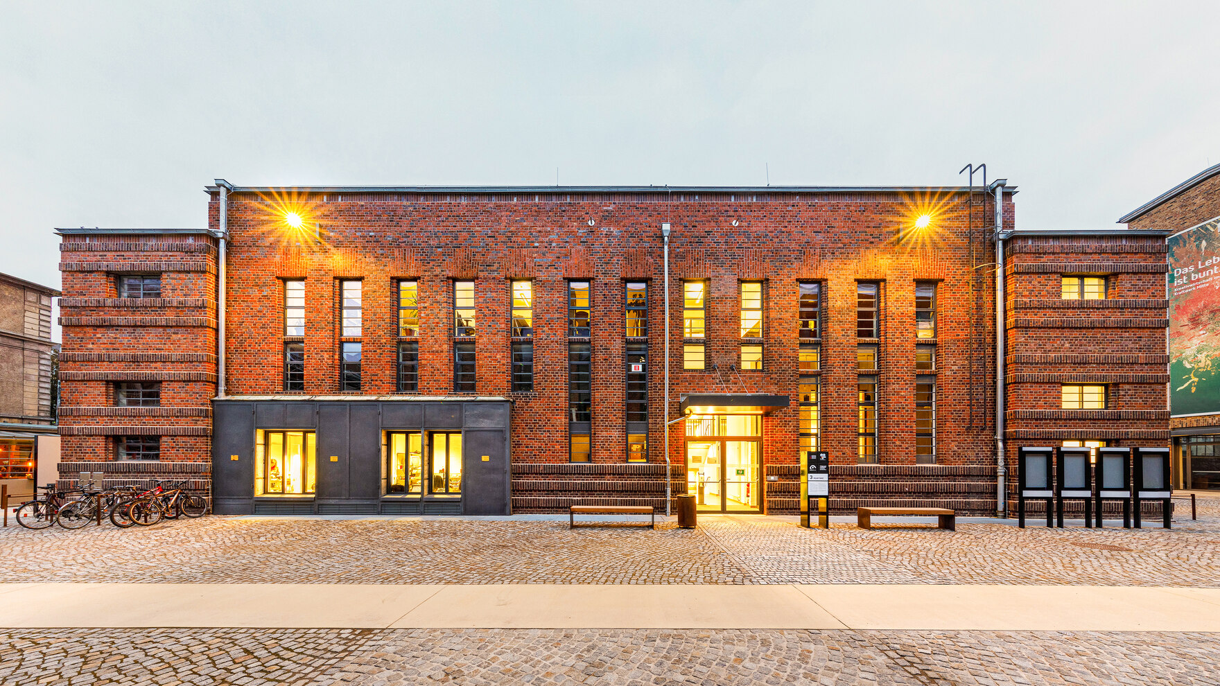 Großes Backsteingebäude mit modernen Fenstern nächtlich beleuchtet
