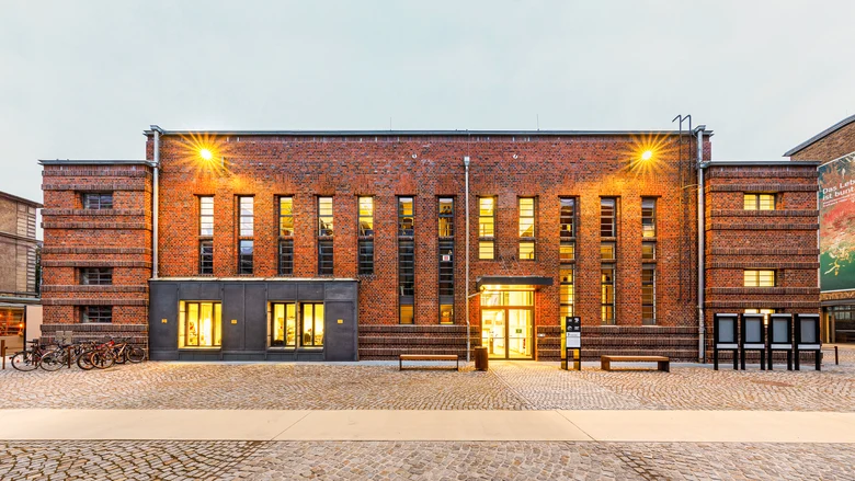 Großes Backsteingebäude mit modernen Fenstern nächtlich beleuchtet