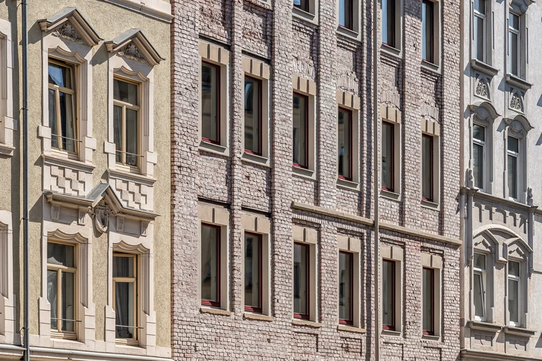Alte Reihenhäuser, alle aus verschiedenen Materialien, in der Mitte ein aus rosafarbenem Backstein