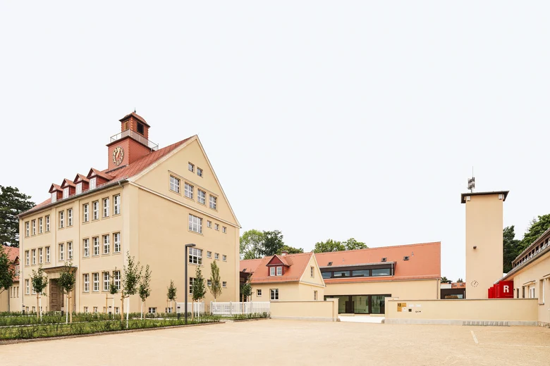 Gebäudekomplex gelb mit roten Dächern, ein Gebäude mit Uhr-Turm