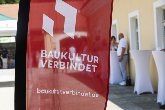 Logo Baukultur verbindet auf einer roten Fahne weht im Wind